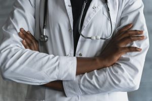 Close-up of a confident doctor in a lab coat standing with crossed arms and stethoscope. — Dr. Scott Kamelle Helping Women Na