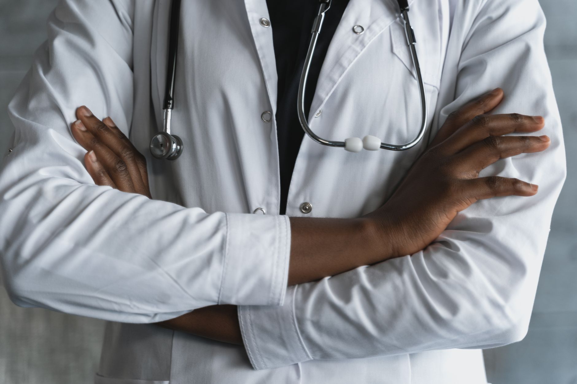 Close-up of a confident doctor in a lab coat standing with crossed arms and stethoscope. — Dr. Scott Kamelle Helping Women Na