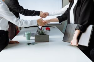 Professionals sealing a deal with a handshake across a conference table during a business meeting. — IronFX MetaTrader 4: Adv