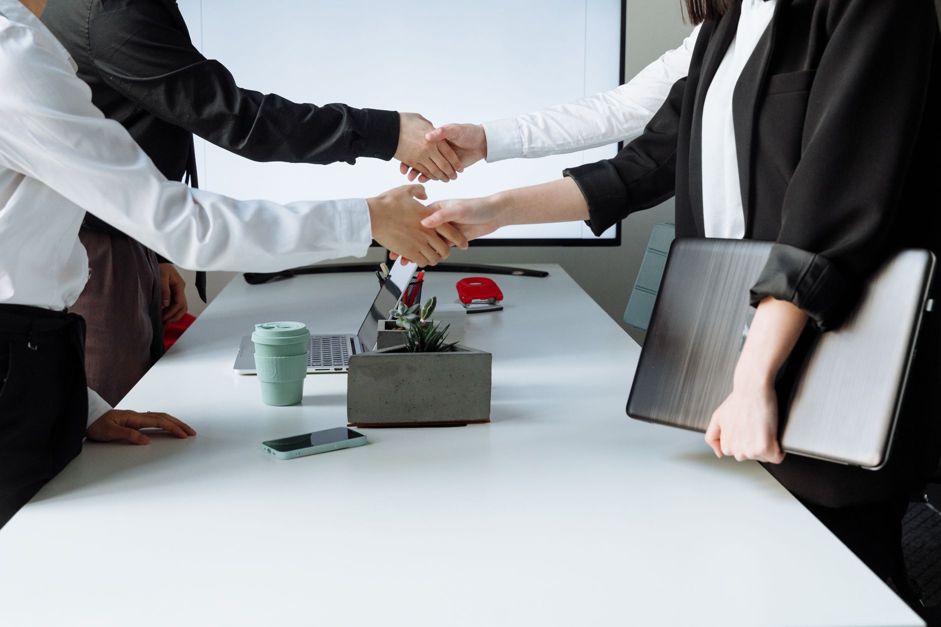 Professionals sealing a deal with a handshake across a conference table during a business meeting. — IronFX MetaTrader 4: Adv