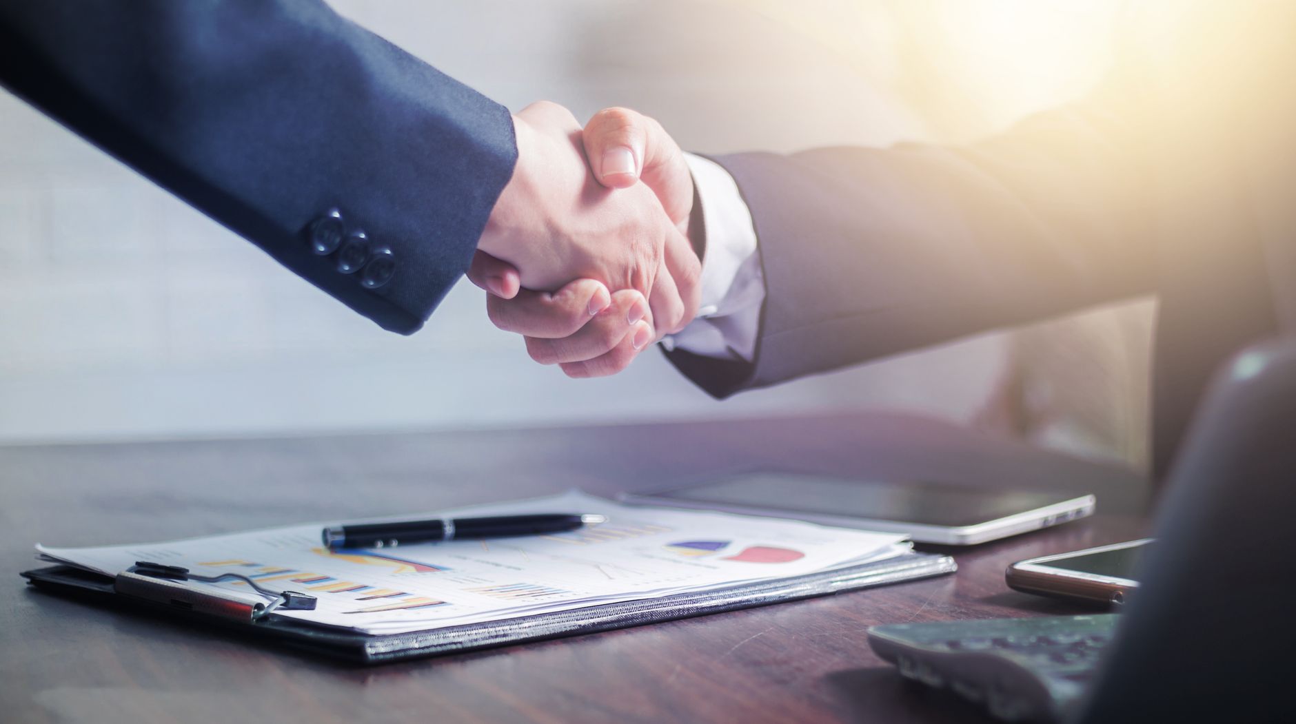Professional handshake agreement over business charts in an office setting. — The Benefits of Dolby Vision in Enhancing Movie